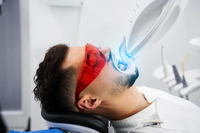 a man is getting his teeth whitened in a dental office .