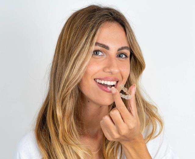 a woman is holding a clear brace in her mouth .