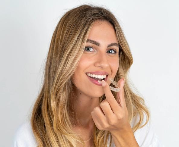 a woman is holding a clear brace in her mouth .