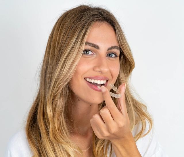 a woman is holding a clear brace in her mouth .