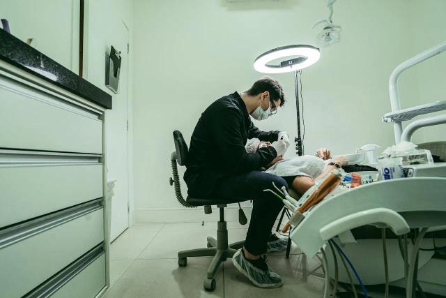 a dentist is examining a patient 's teeth in a dental office .