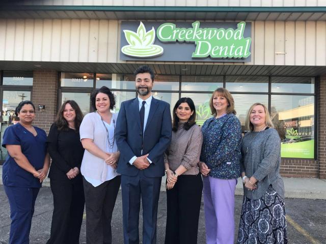 a group of people are posing for a picture in front of a dental office .