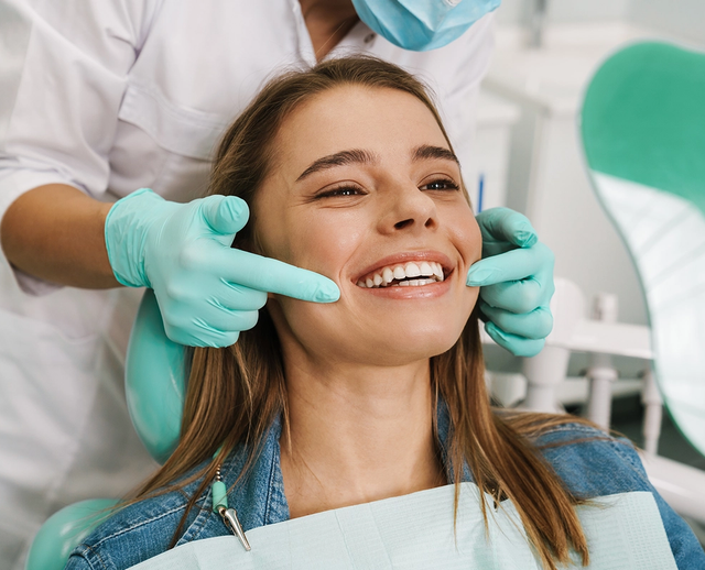 a woman in a dental chair is smiling while a dentist examines her teeth