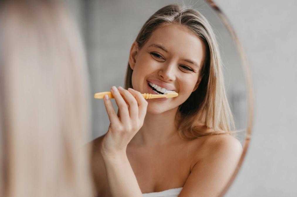 a woman is brushing her teeth in front of a mirror .