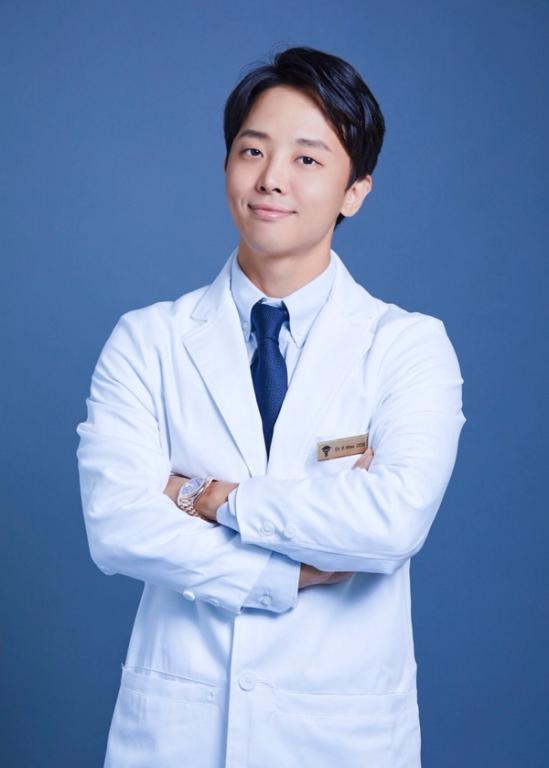 a man in a white coat and tie has a name tag that says dr. s. kim