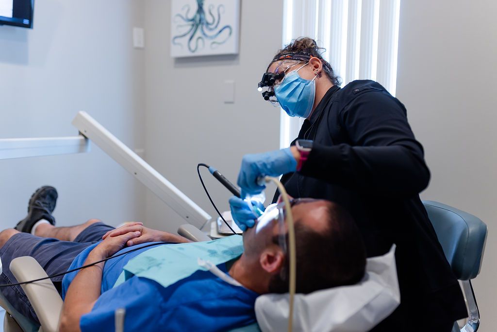 a dentist is examining a patient 's teeth in a dental office .