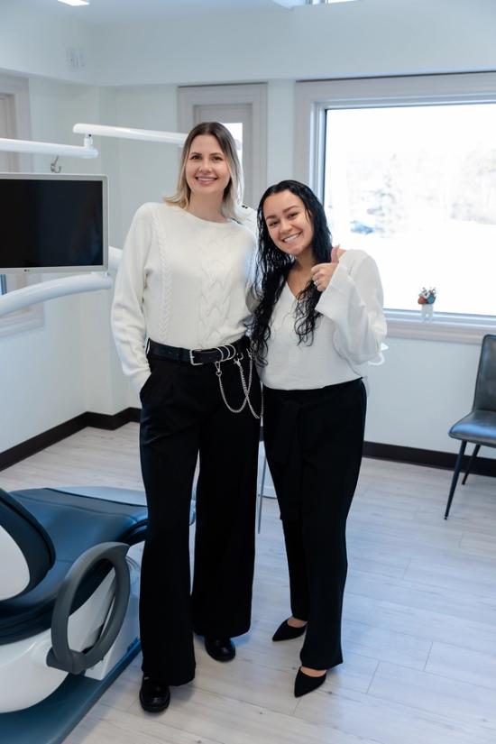 two women are posing for a picture in a dental office