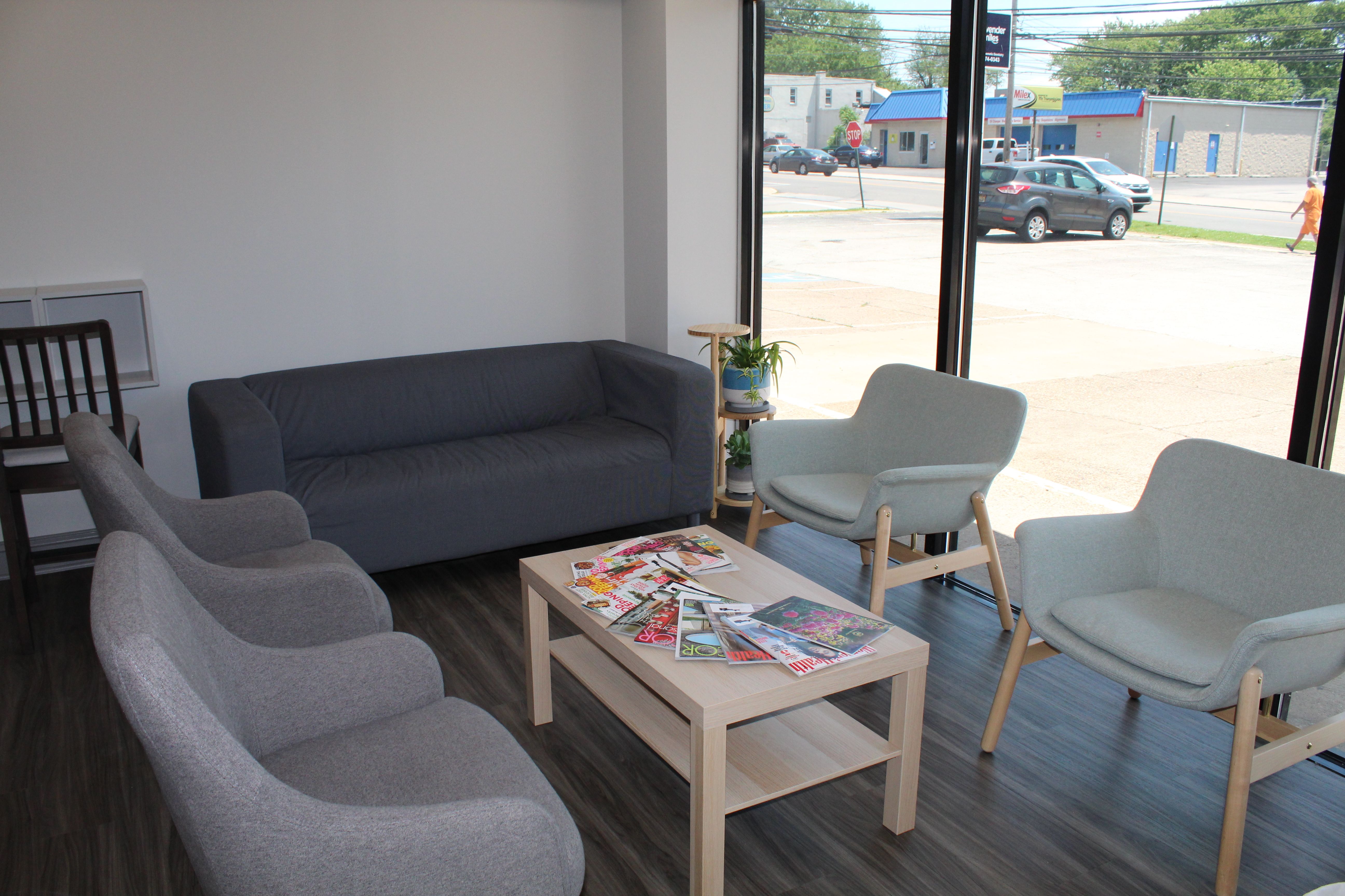 a waiting room with a couch , chairs , and a coffee table .