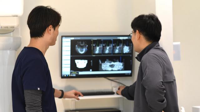 two men are looking at a computer screen in a dental office .