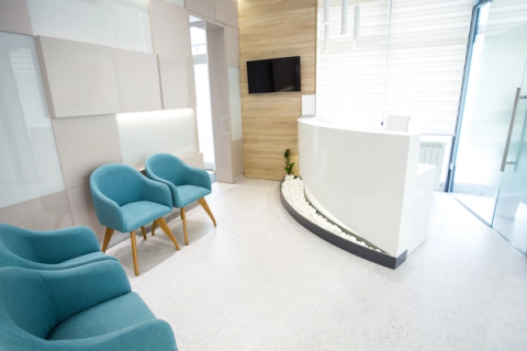 a waiting room with blue chairs and a white counter