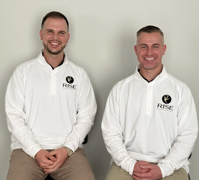 Two smiling men in matching white Rise Modern Dentistry pullovers.