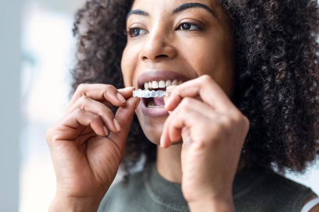 a woman is putting invisible braces on her teeth .