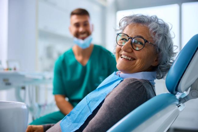 an elderly woman is smiling while sitting in a dental chair .