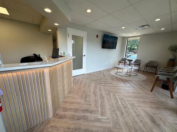 a waiting room with a desk , chairs , tables and a television .
