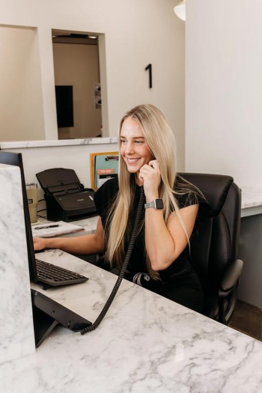 a woman sitting at a desk talking on a phone with the number 1 on the wall behind her