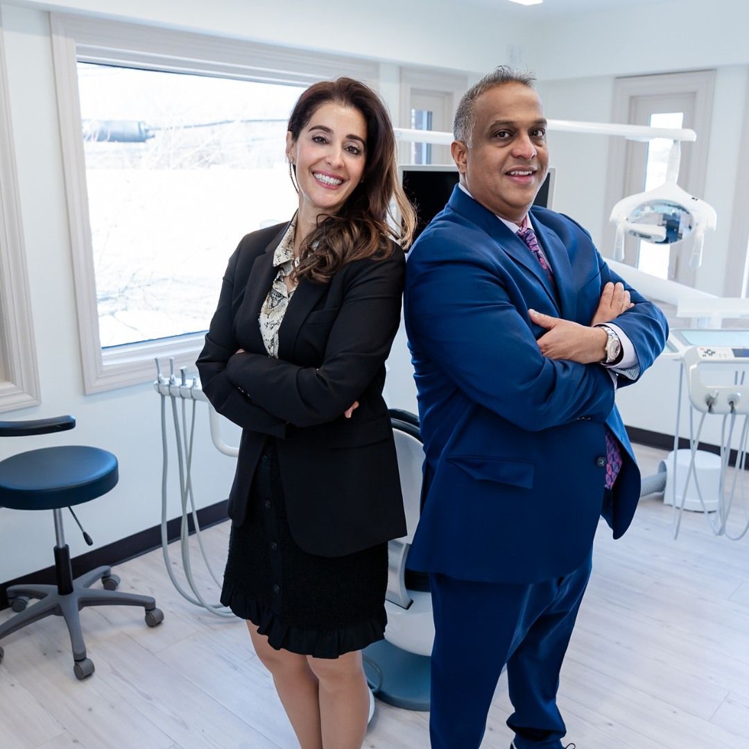 a man and a woman are standing back to back in a dental office .