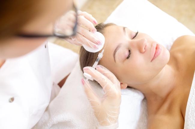 a woman is getting an injection in her forehead at a beauty salon .