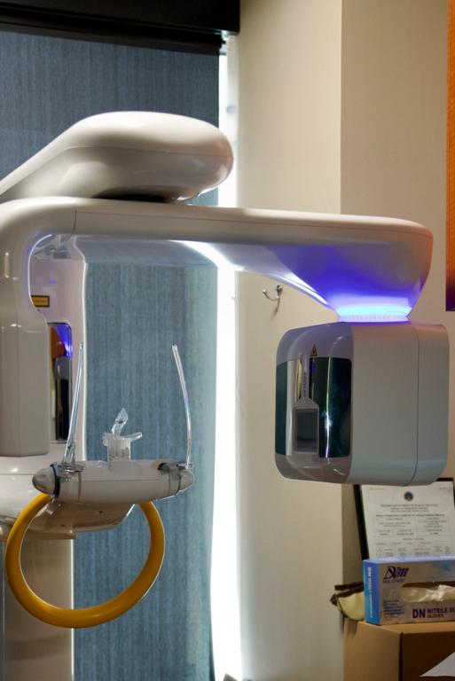 A white panoramic dental X-ray machine with a blue light and a yellow chin rest.