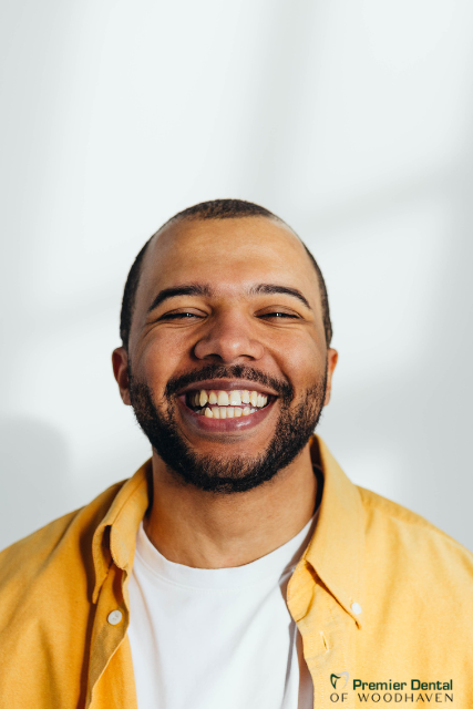 a man wearing a yellow shirt that says premier dental of woodhaven