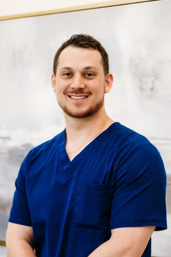 a man wearing a black scrub top with the name damian on it