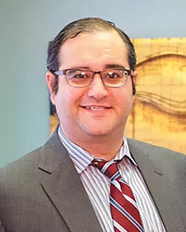 a man in a suit and tie is smiling for the camera .