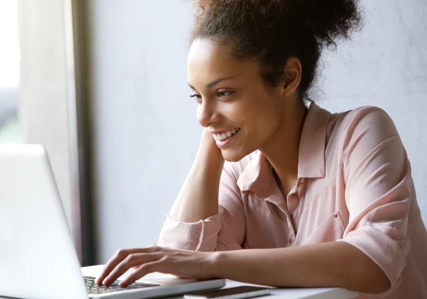 a woman is smiling while using a laptop computer .