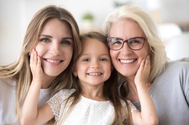 a mother , daughter and grandmother are posing for a picture together .