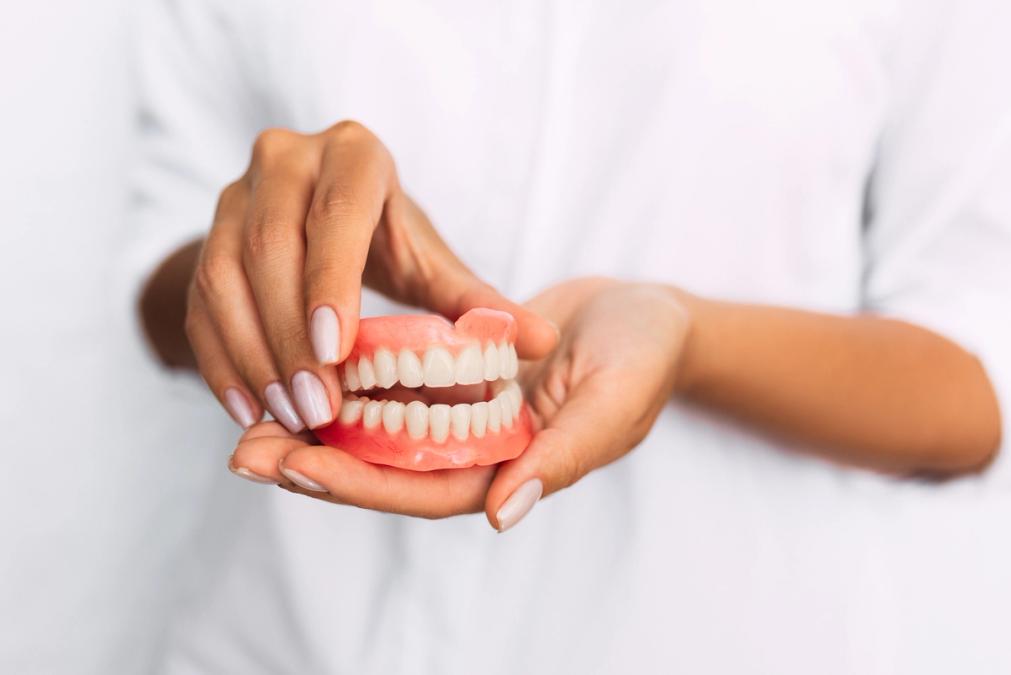 a woman is holding a model of dentures in her hands .