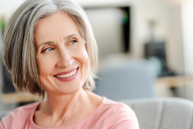 a woman with gray hair is smiling while sitting on a couch .