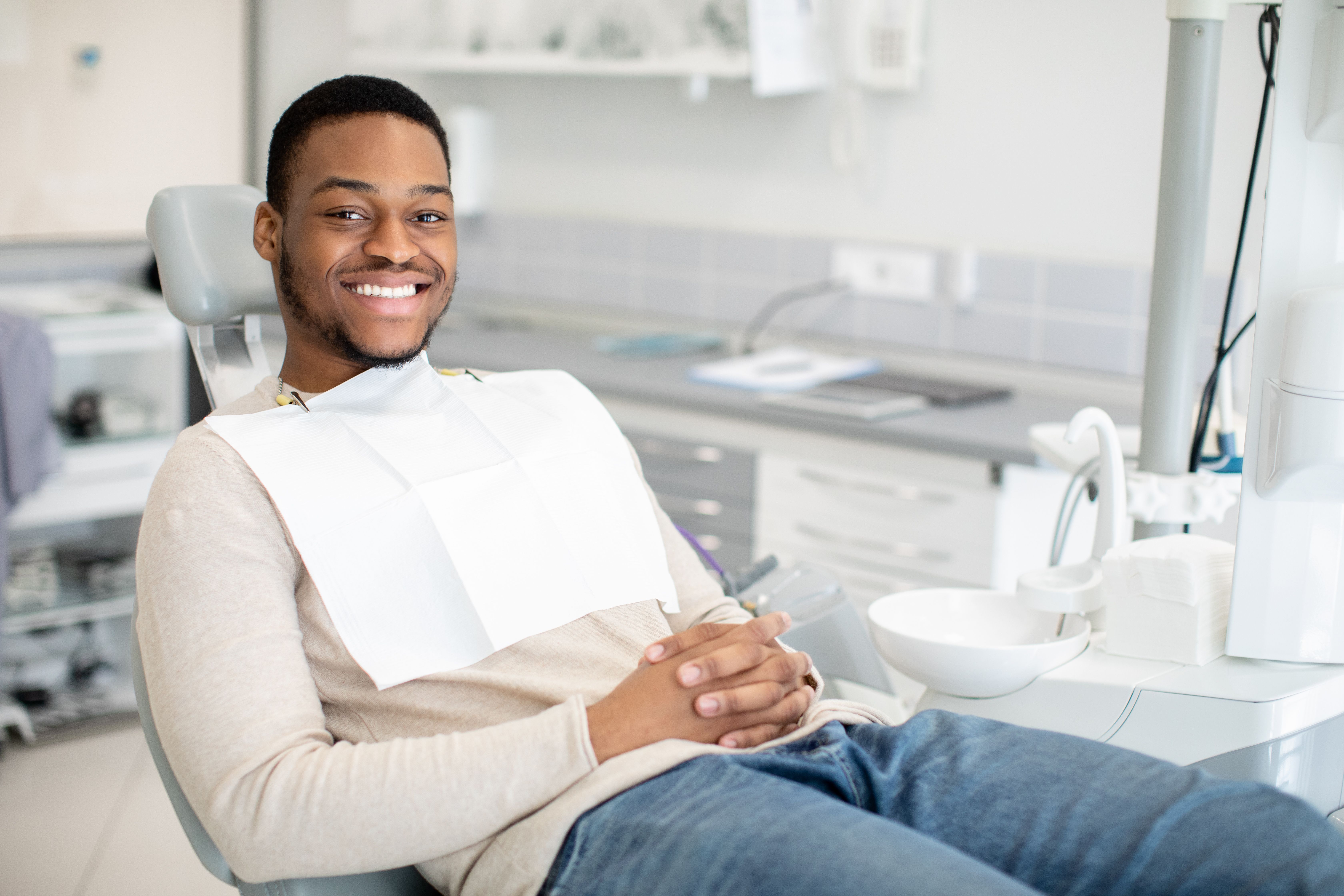 a man is sitting in a dental chair and smiling .