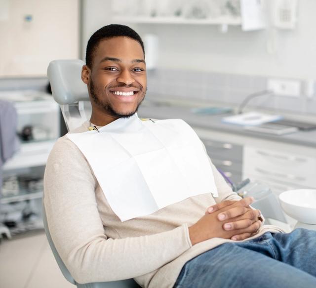 a man is sitting in a dental chair and smiling .