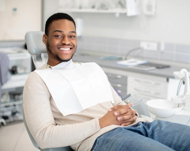 a man is sitting in a dental chair and smiling .