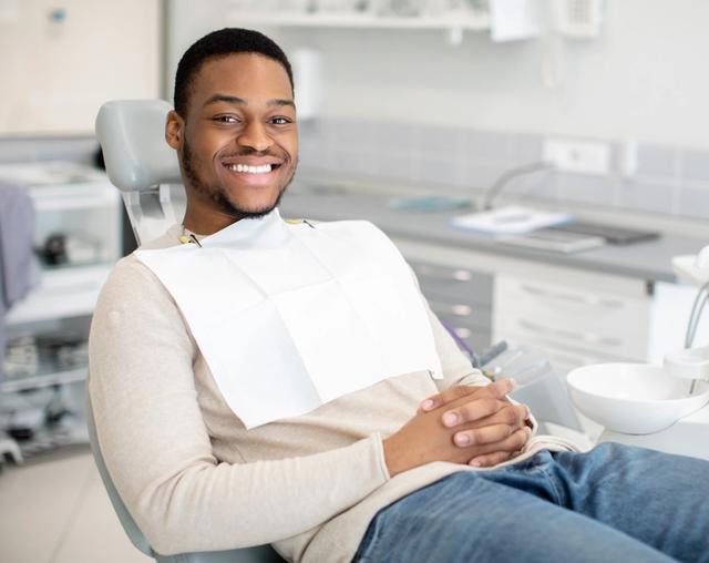 a man is sitting in a dental chair and smiling .