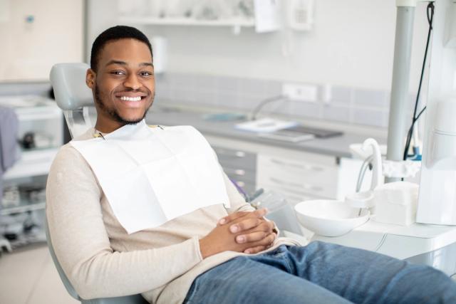 a man is sitting in a dental chair and smiling .