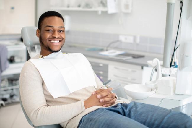 a man is sitting in a dental chair and smiling .