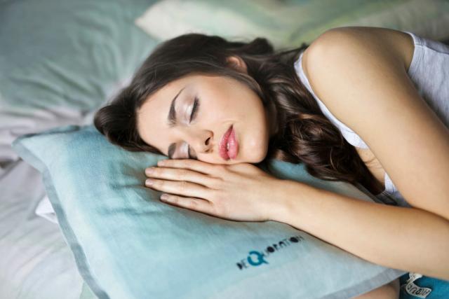 a woman is sleeping on a bed with a blue pillow .
