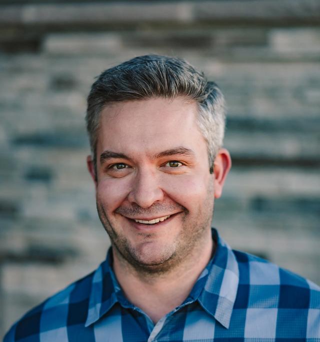 a man in a black scrub top is smiling for the camera .