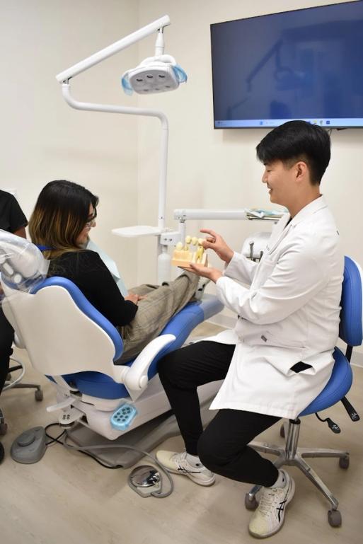 A dentist explains a dental model to a patient in a dental chair.