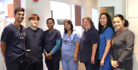 Seven smiling healthcare professionals in scrubs.