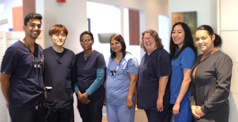 Seven smiling healthcare staff members in scrubs.