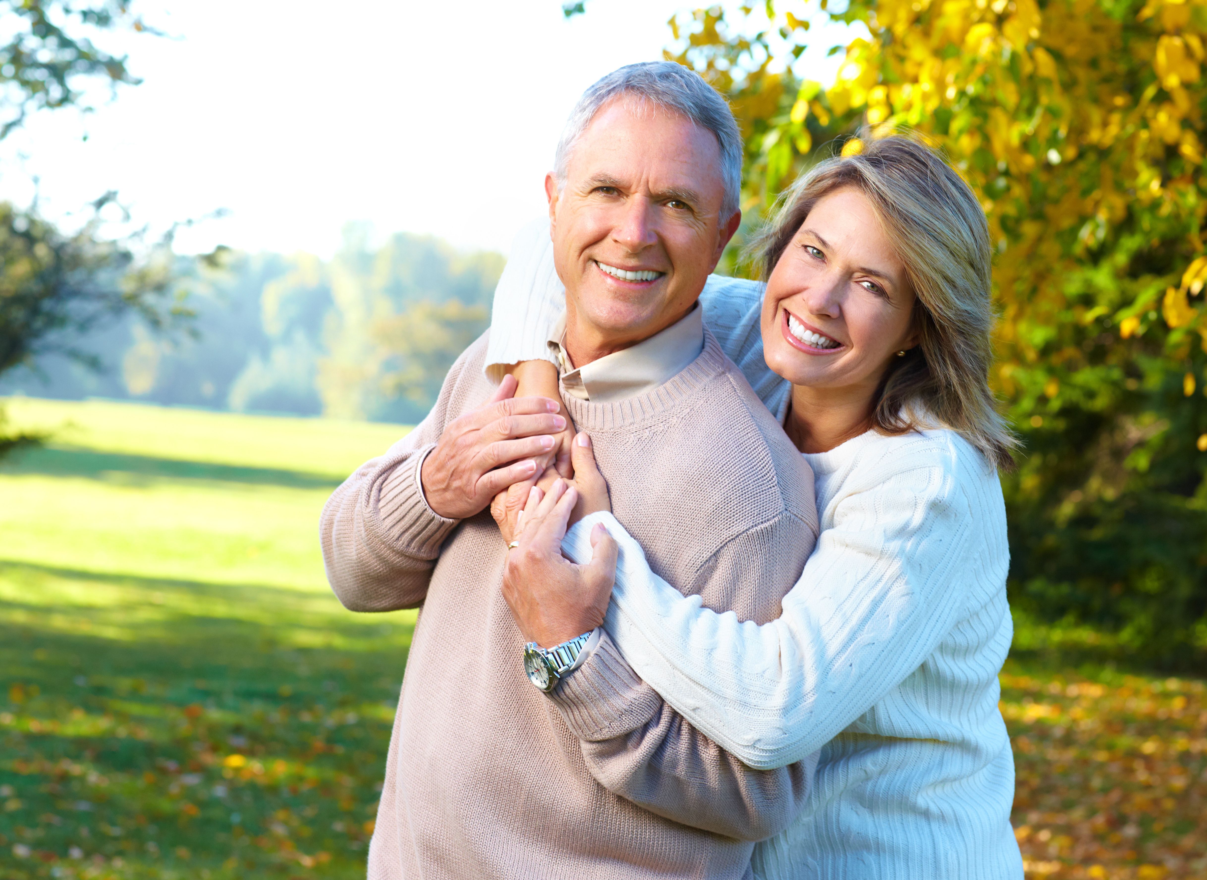 a woman is hugging a man in a park .