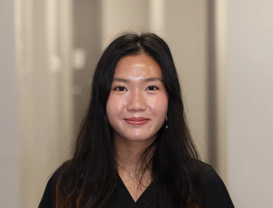 a woman wearing a black shirt and a necklace smiles for the camera