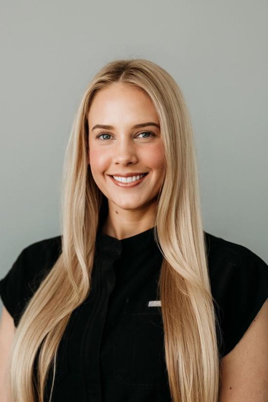 a woman with long blonde hair is wearing a black shirt and smiling