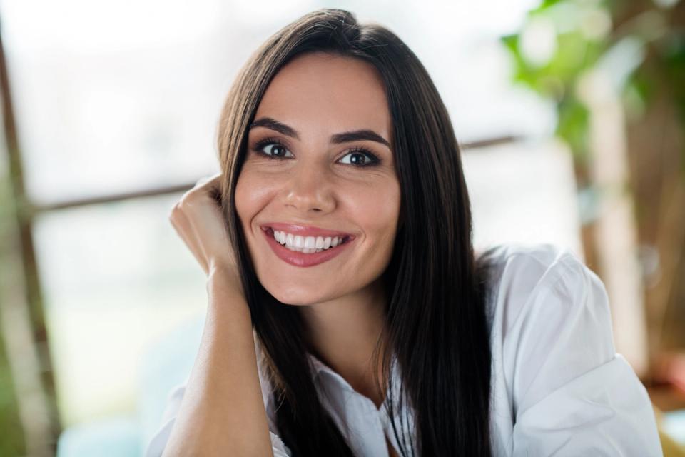 a close up of a woman smiling with her hand on her face .