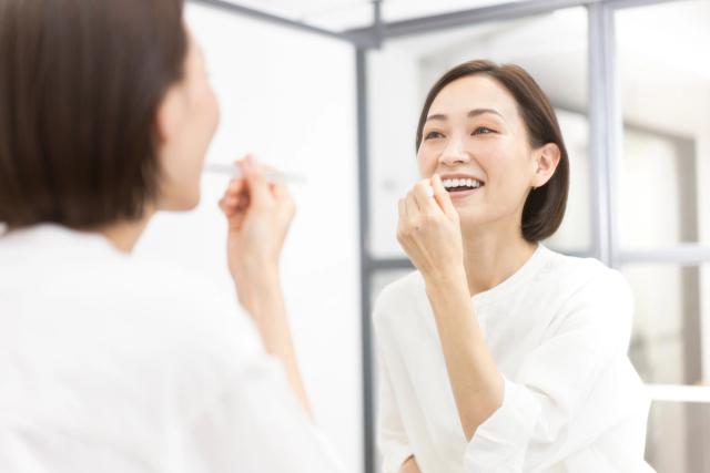 a woman is brushing her teeth in front of a mirror .