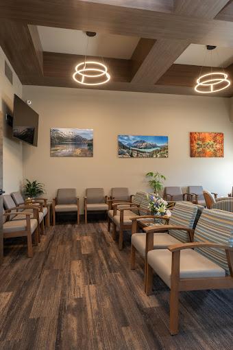 a waiting room with wooden floors , chairs , tables and a flat screen tv .