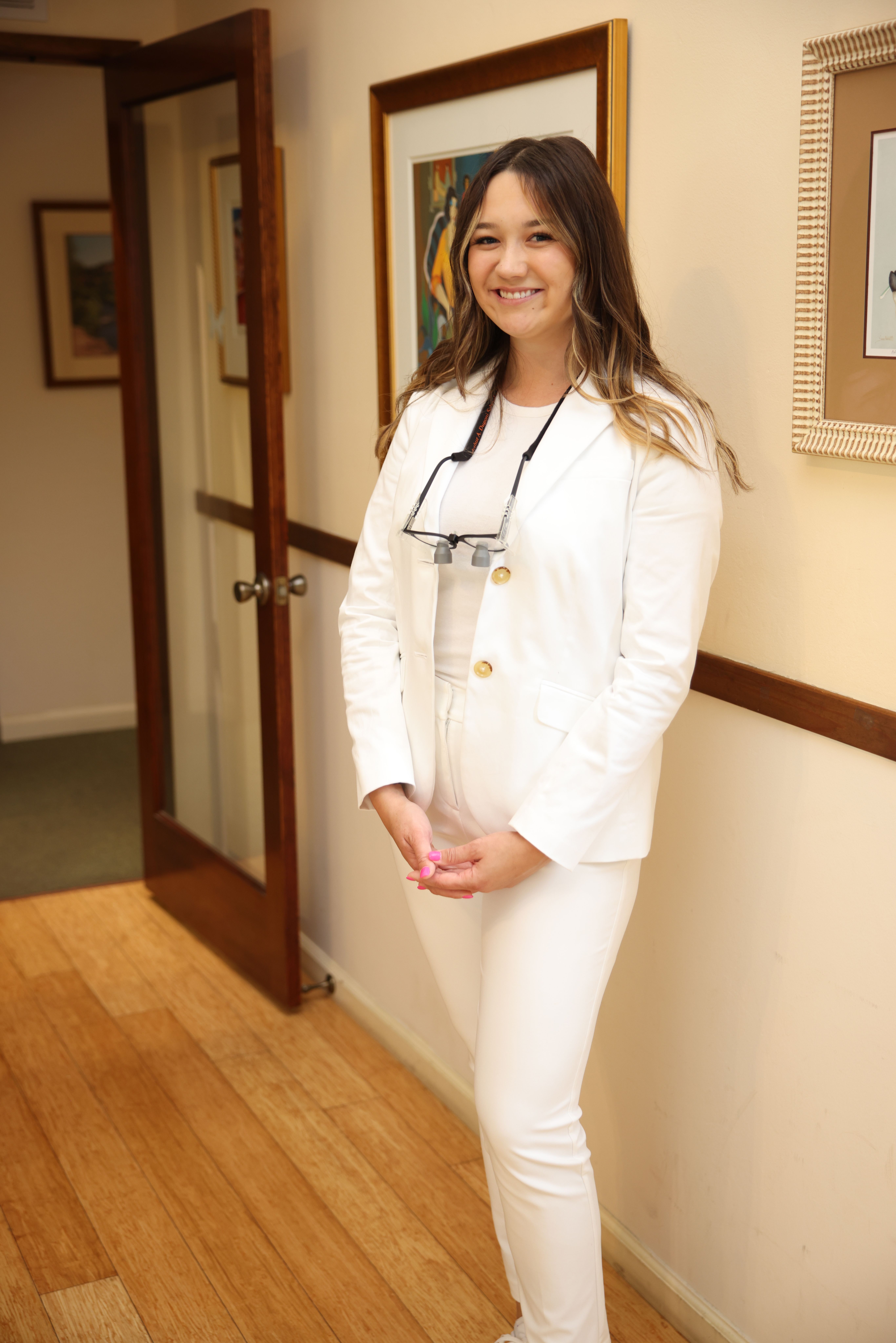 a woman in a white suit is standing in a hallway .