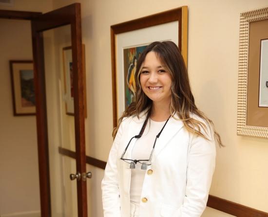 a woman in a white suit is standing in a hallway .