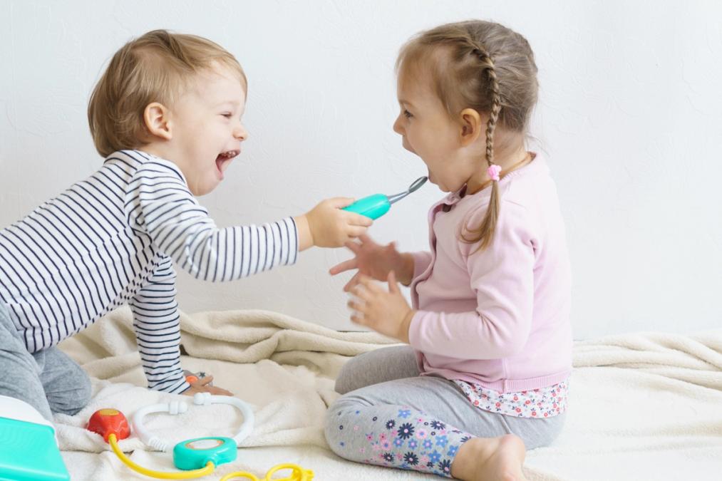 a boy and a girl are playing with toys on a bed .