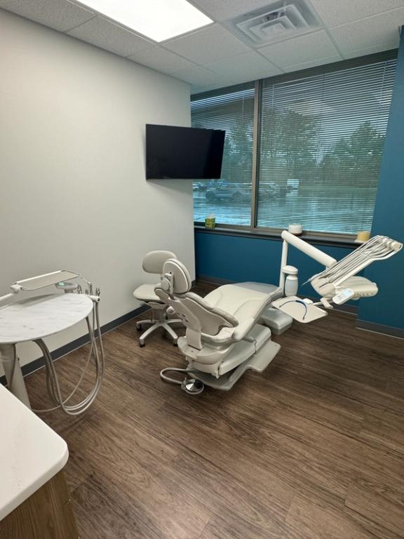 a dental office with a dental chair and a flat screen tv